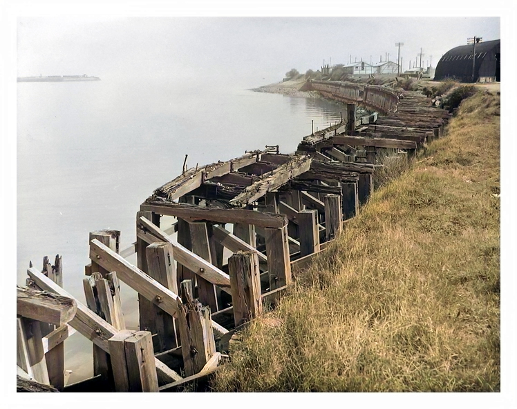 1950's - A view downstream from the slipway and gridiron location showing the derelict timber shoring on the Penarth Dock bank of the River Ely Estuary. 