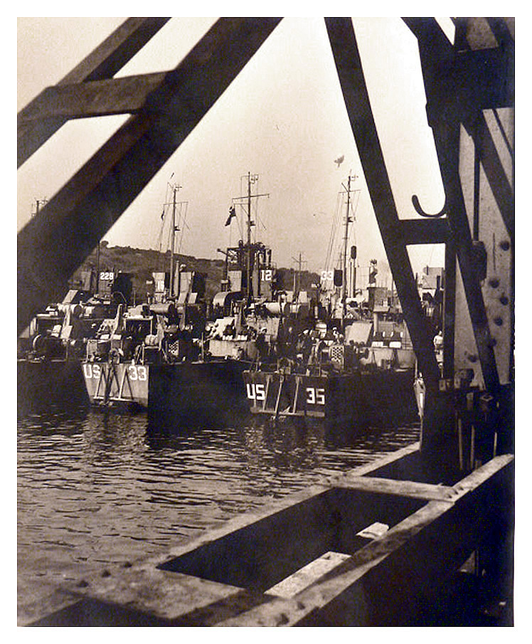 1943-4 - Another peek through the ironwork of a dockside crane at the LST's. Nearest the quaywall we see US-35, US-33, US-12, US-15, and US-229. 
