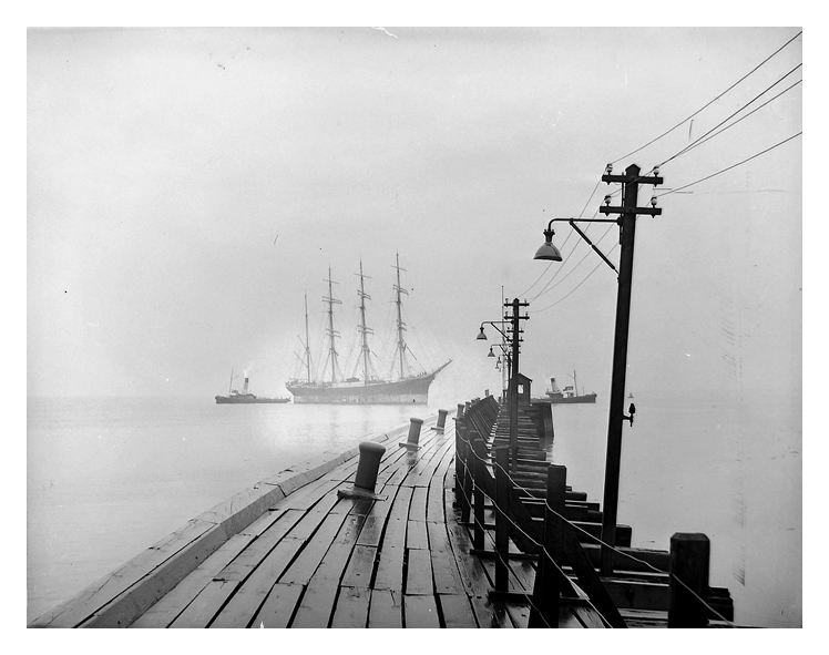 1950 - The Finnish barque 'Passat' under tow of two tugs approaching the southern entrance pier of Penarth Dock on a misty, rainy day.