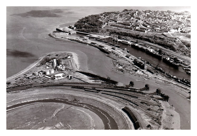 1949-1950 - An aerial view of the location of the former iron-ore wharf as re-purposed to the petroleum wharf with associated oil storage tanks and processing facilities. 